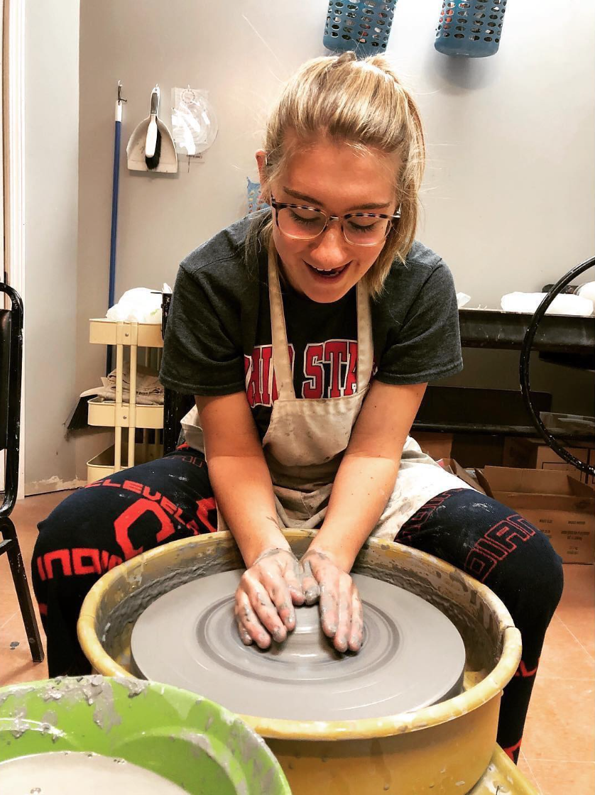 A woman is enjoying a girls' night out working on a pottery wheel.