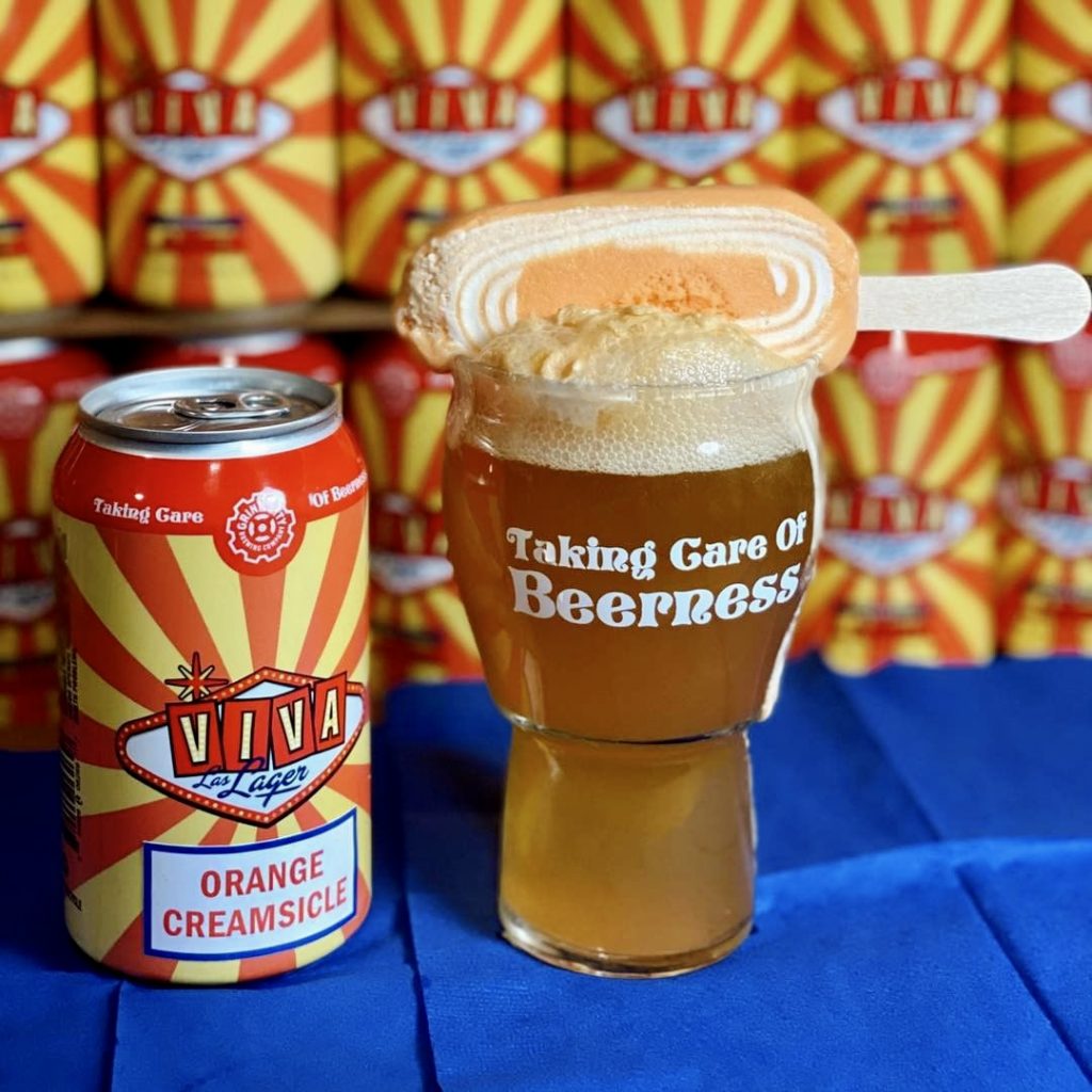 A can of orange creamsicle beer next to a popsicle in breweries.