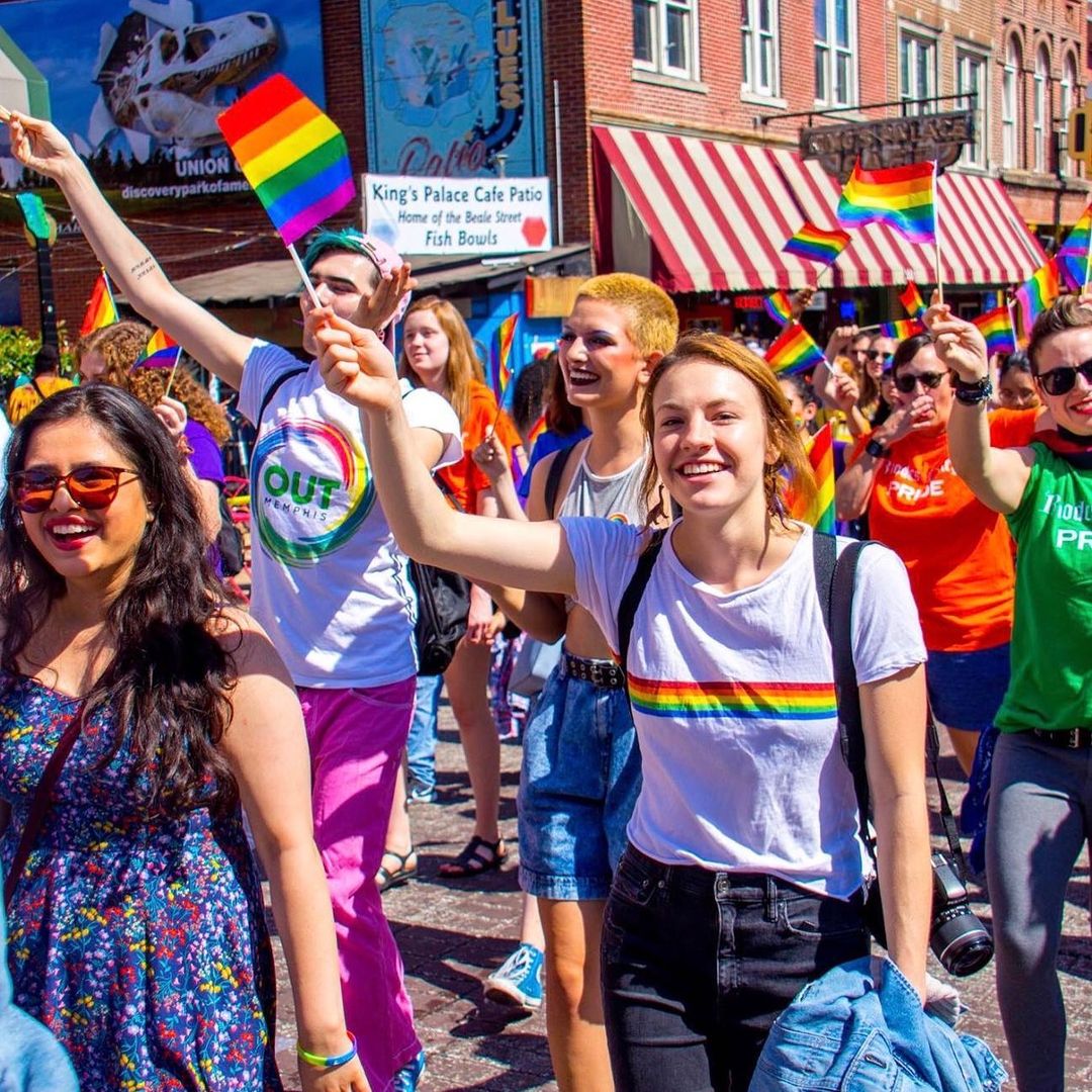 A group of people waving rainbow flags in Memphis, representing the LGBTQ+ community.