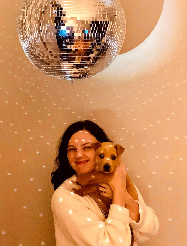 A Memphis woman fostering a dog poses in front of a disco ball.