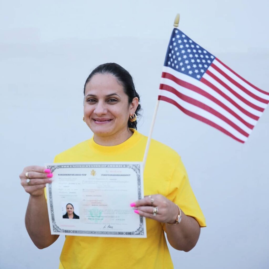 A Latinx woman proudly waving an American flag while holding a certificate in Memphis.