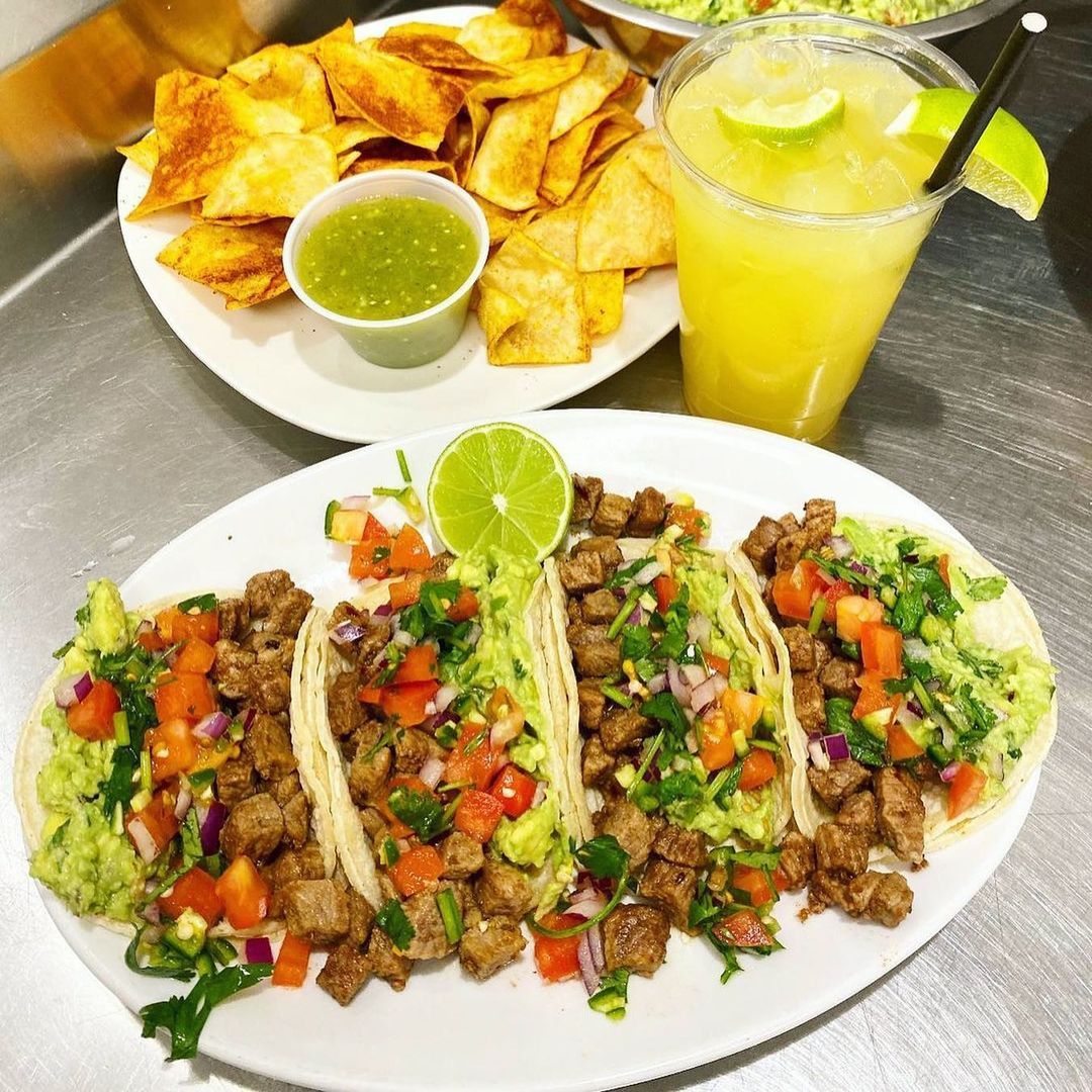 A plate of tacos and guacamole on a table.