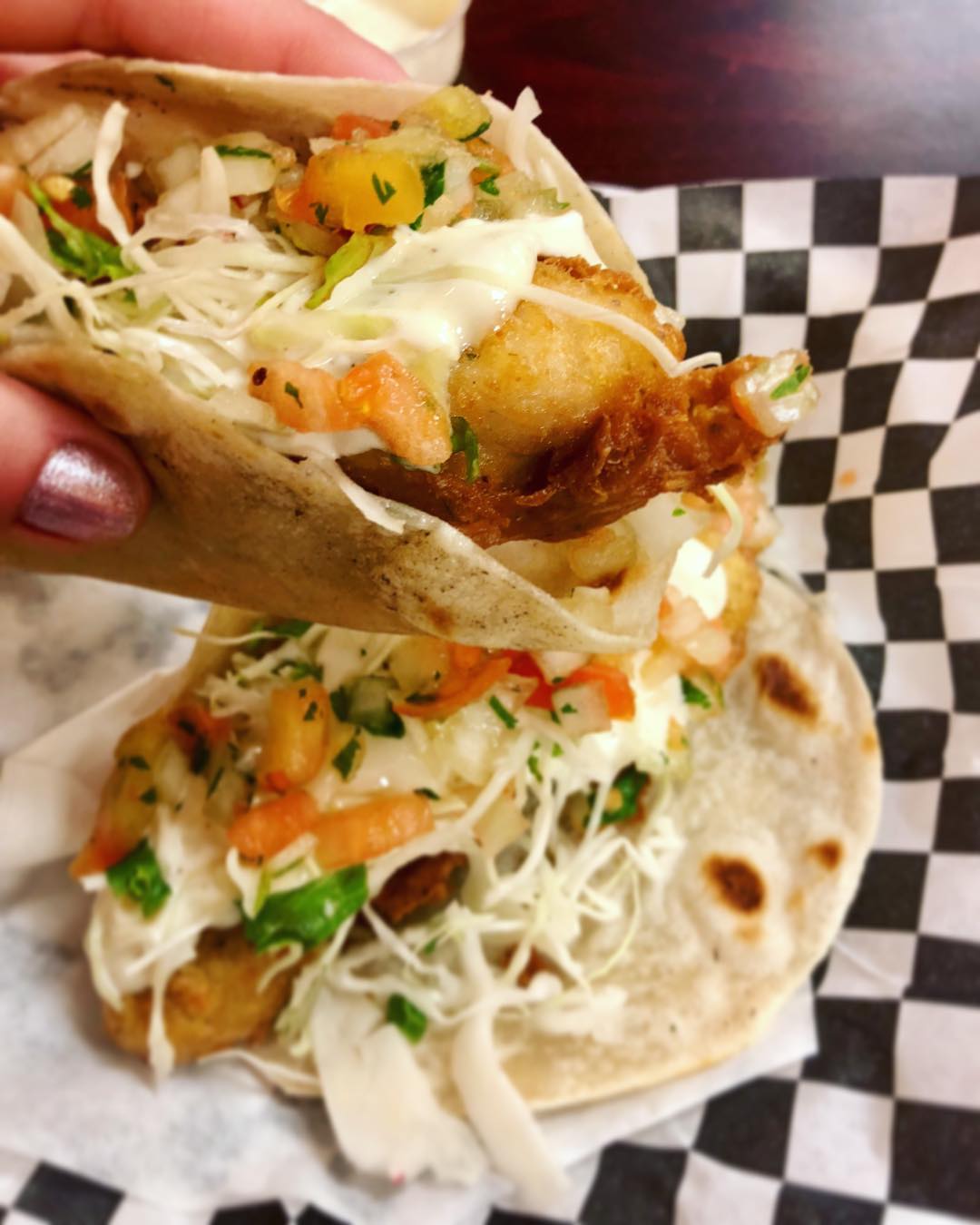 A person holding up a fish taco.
