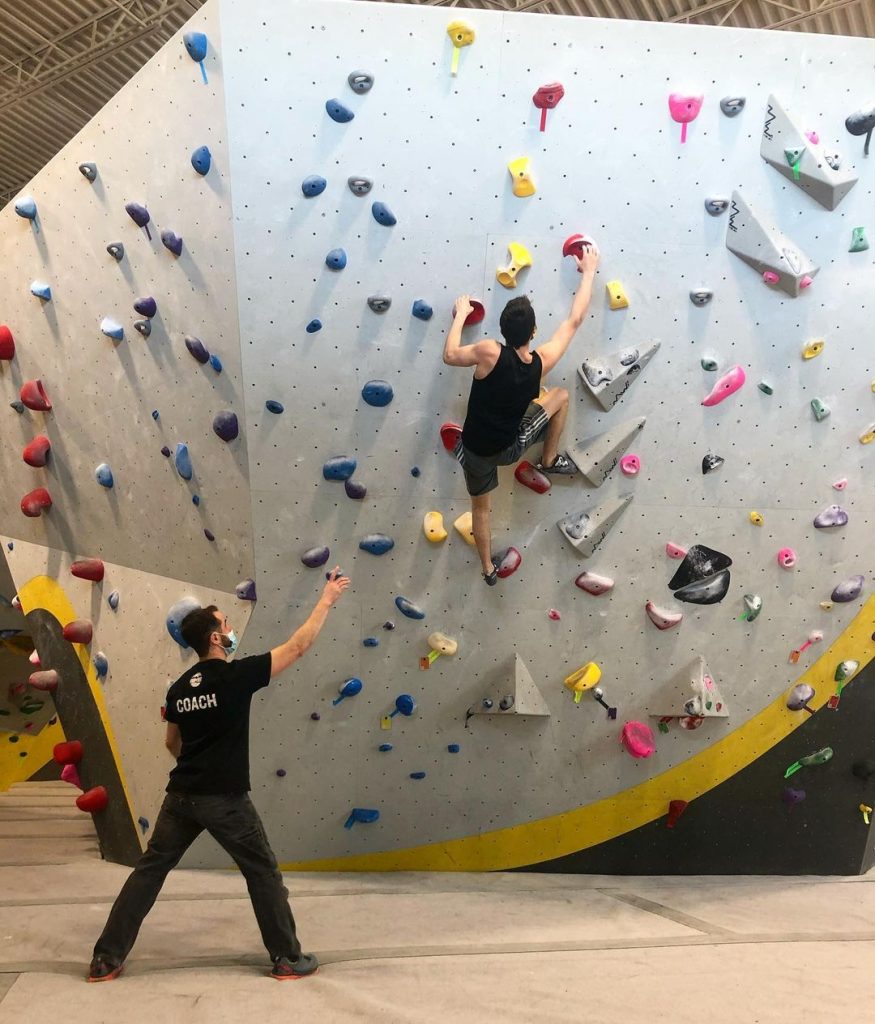 A man is climbing on a gym wall.