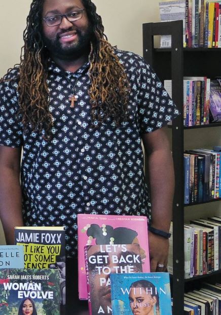 A man standing in front of a table full of books celebrating black history month.