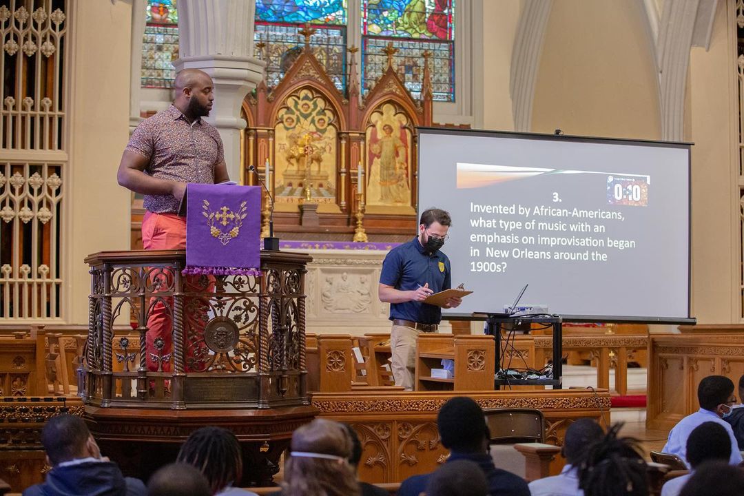 A man standing at a podium in front of a church delivering a history lesson to middle schoolers.