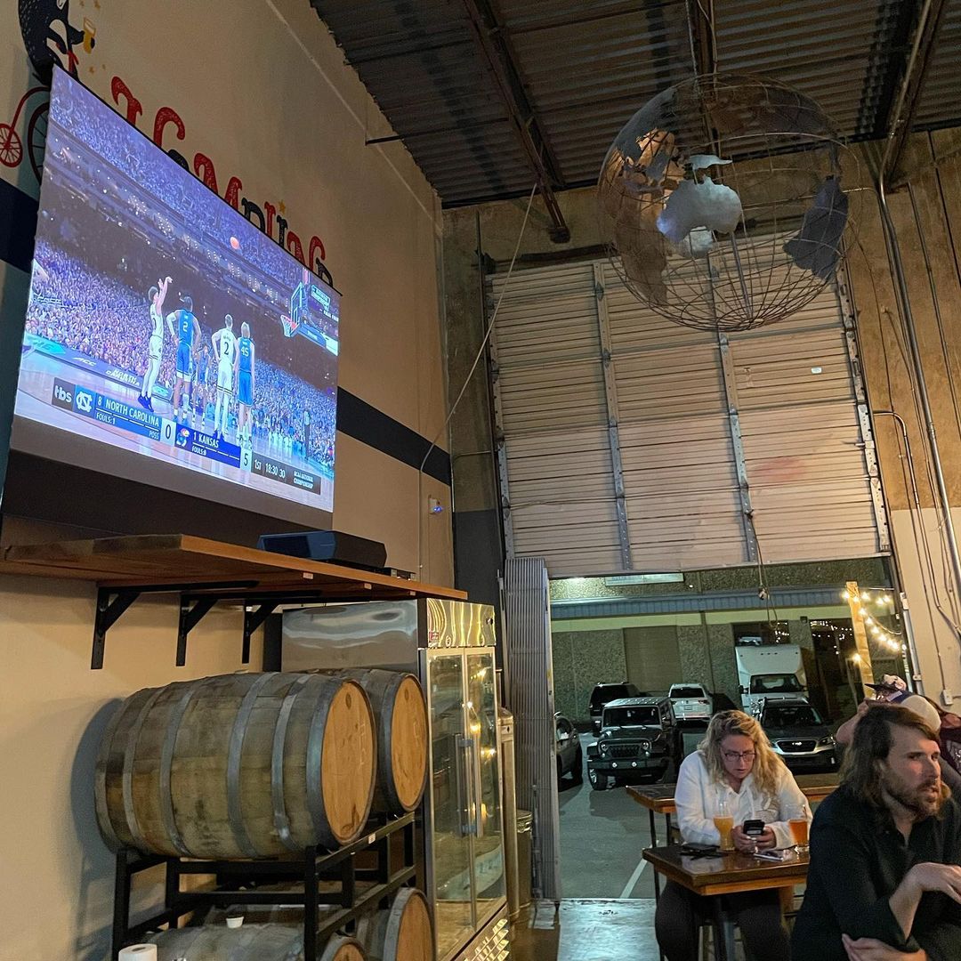 A group of Grizzlies fans watching a TV in a brewery during watch parties.