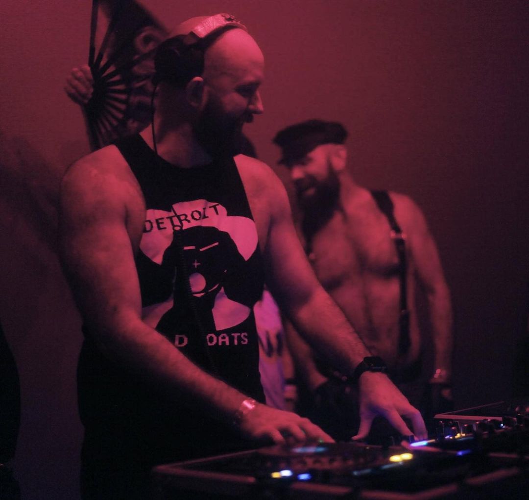 A group of men standing around a dj booth.