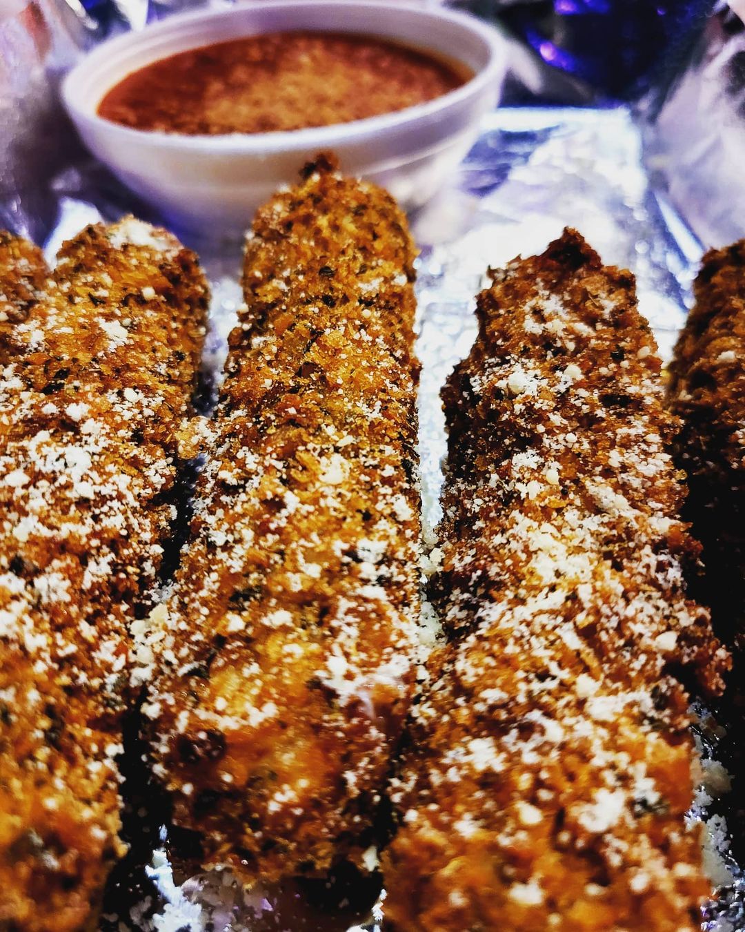 A plate of fried chicken sticks with dipping sauce.
