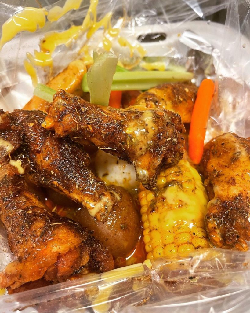 Chicken wings in a plastic bag with carrots and corn.