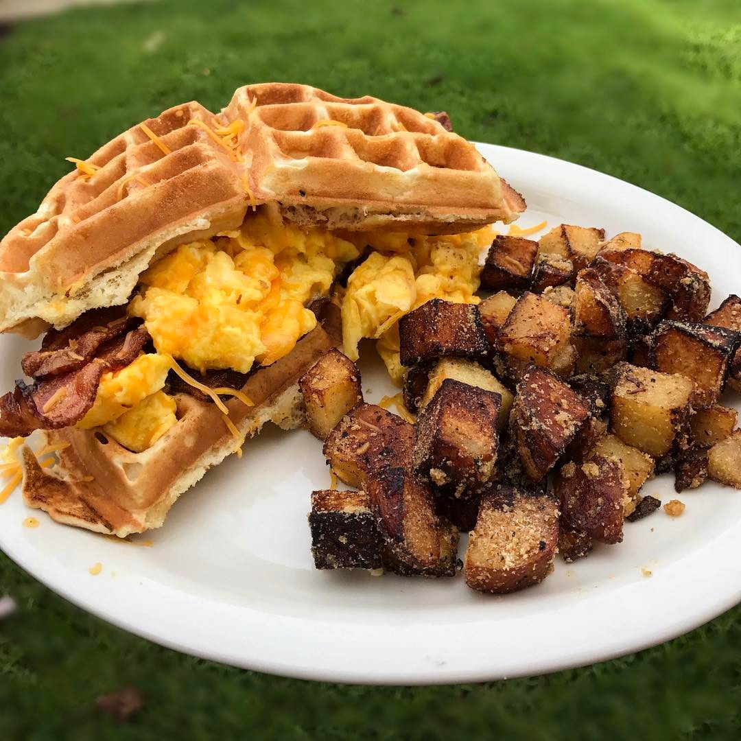 Waffles with bacon and potatoes on a plate.