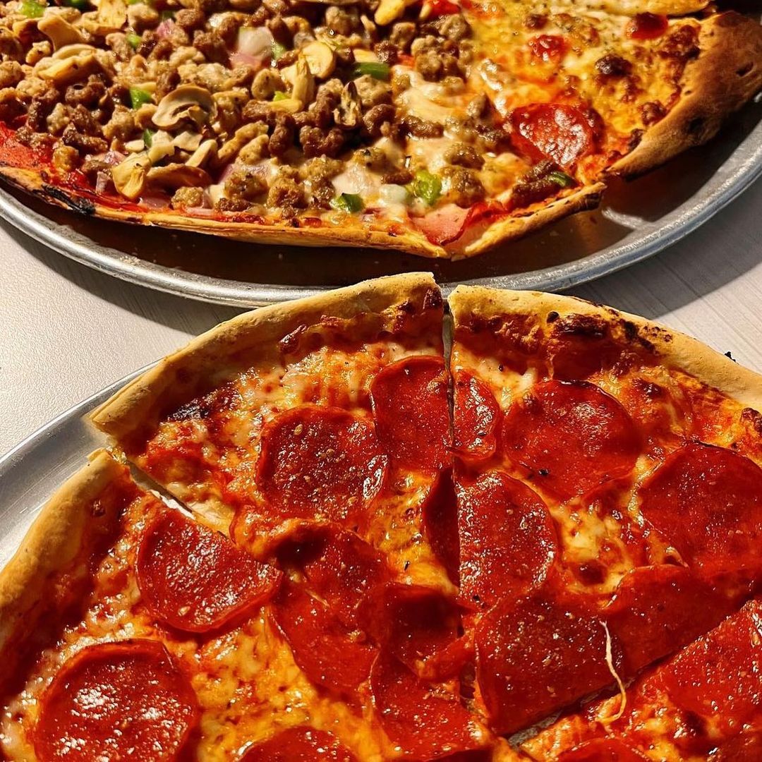 Two pepperoni pizzas on a table next to each other.