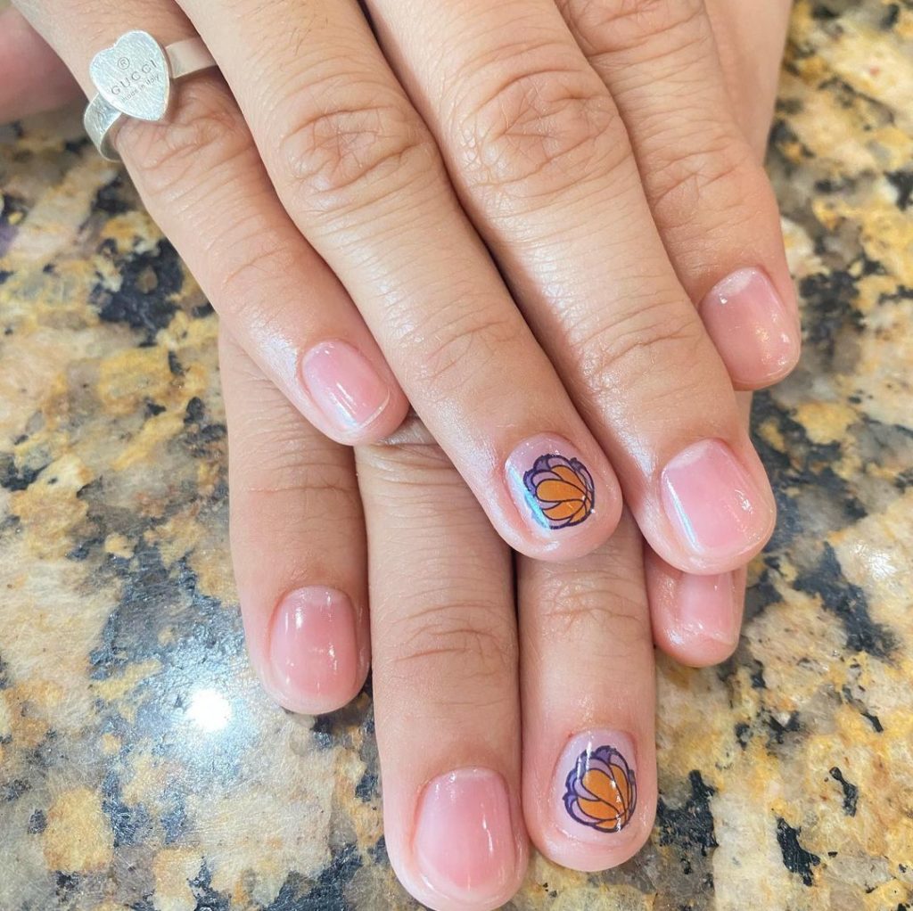 A woman's hands with nails decorated with basketballs.