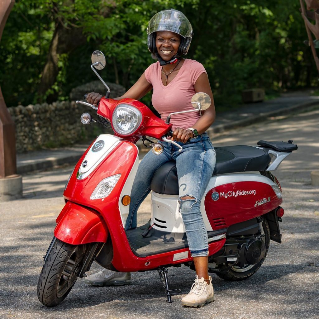 A woman sitting on a red and white scooter.