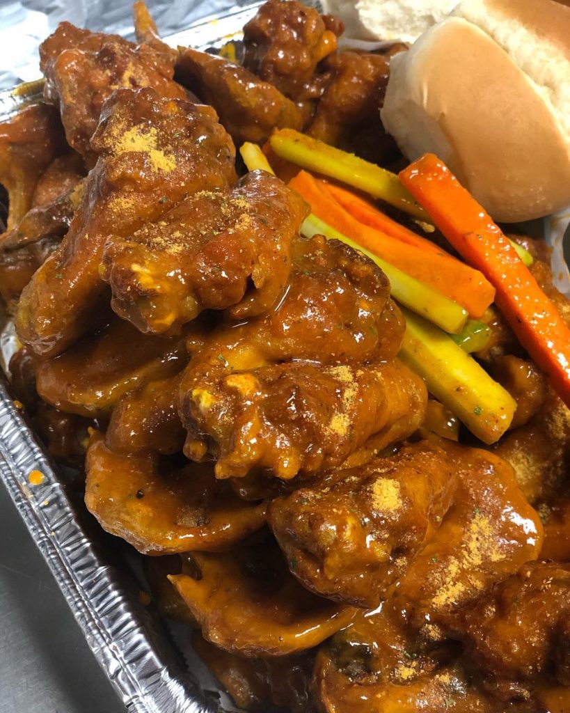 A tray with chicken wings, carrots, and bread.