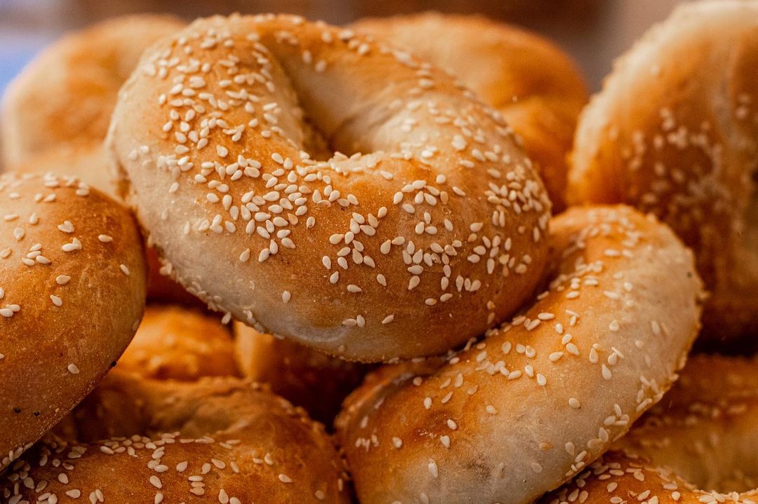 A pile of bagels with sesame seeds on them.
