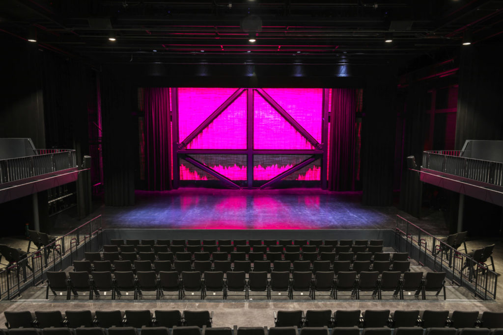 A large auditorium with a pink light shining on it.