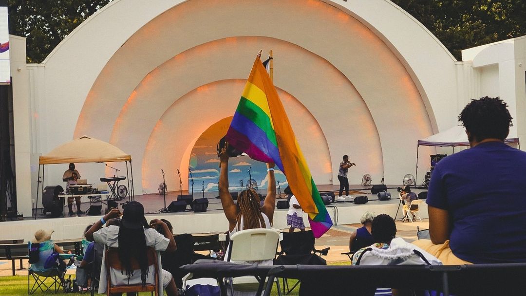 A group of people celebrating Juneteenth in Memphis, watching an outdoor concert with a rainbow flag.