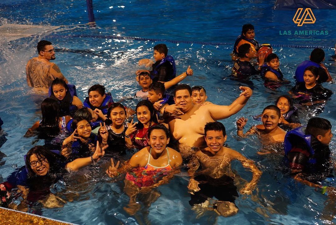 A group of people posing for a picture at Las Americas indoor pool.