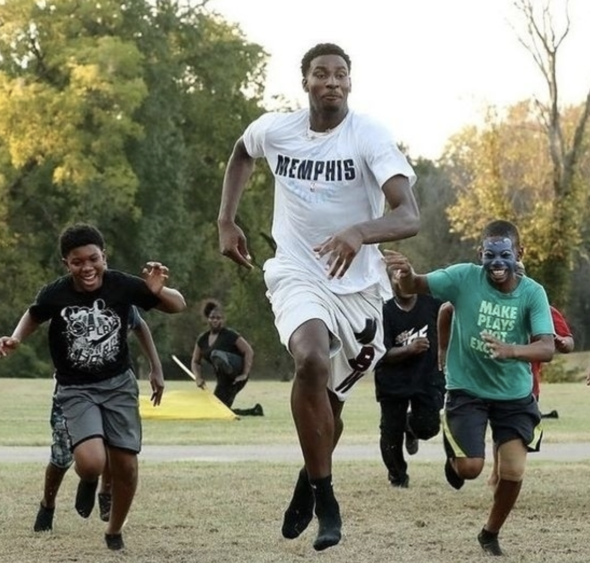 A group of young men participating in a mentoring program while running in a park.