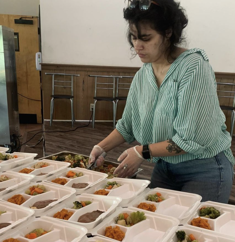 A generous woman is preparing food for a large group of people.
