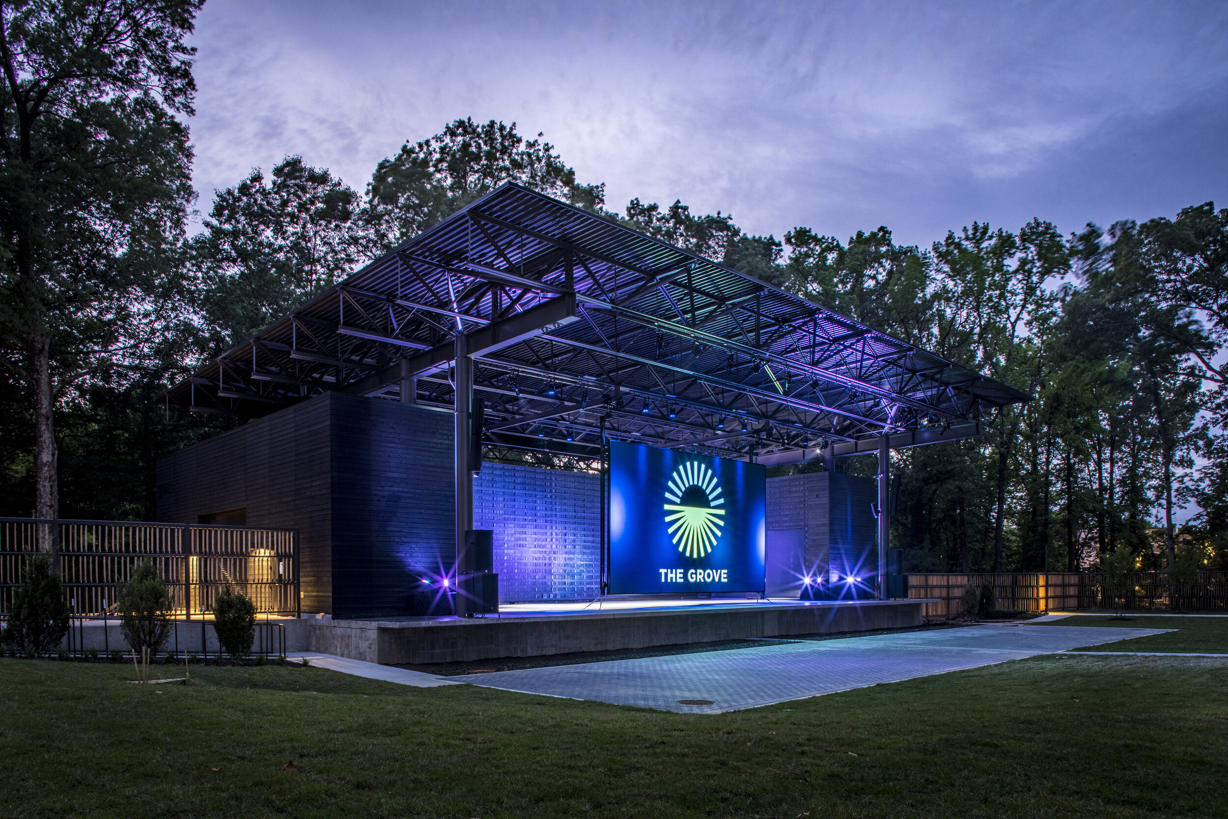 A stage in the middle of a grassy field at dusk.