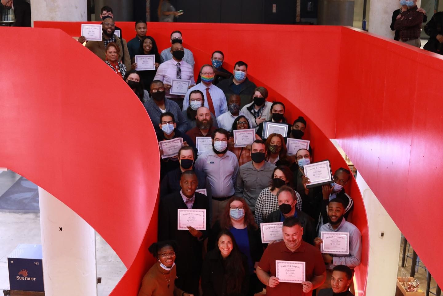 A group of Tech901 graduates posing in front of a red staircase.