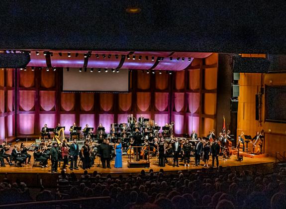An orchestra performing on stage in a large auditorium.