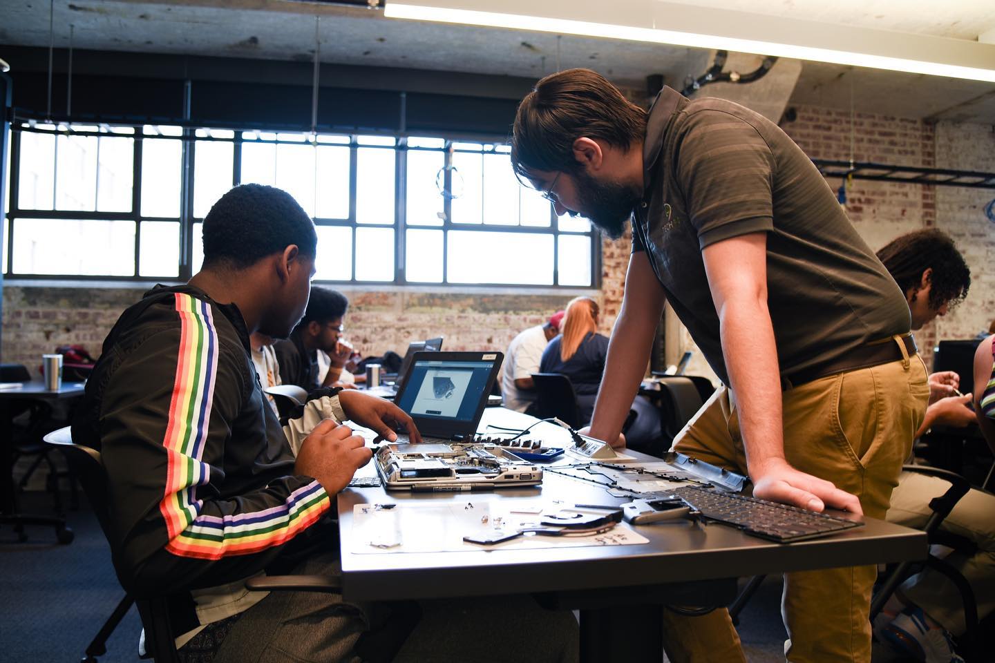 A group of people in the Memphis Tech Industry working on laptops in a classroom.