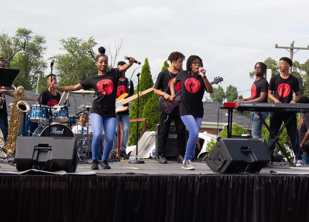 A group of people performing at an outdoor Bike For Education event.