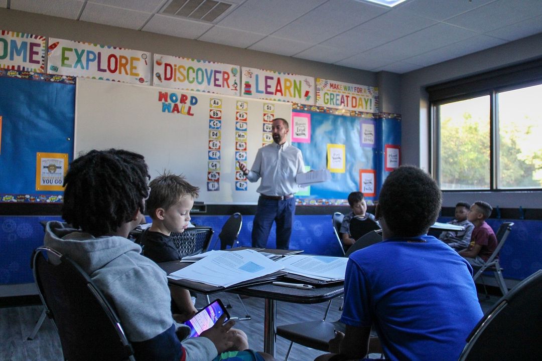 A man addresses children during a classroom discussion.