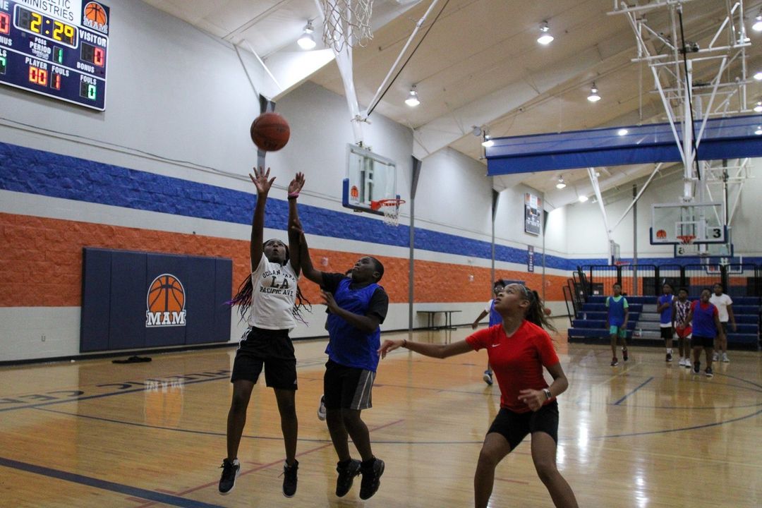 A group of young people playing basketball in a gym.