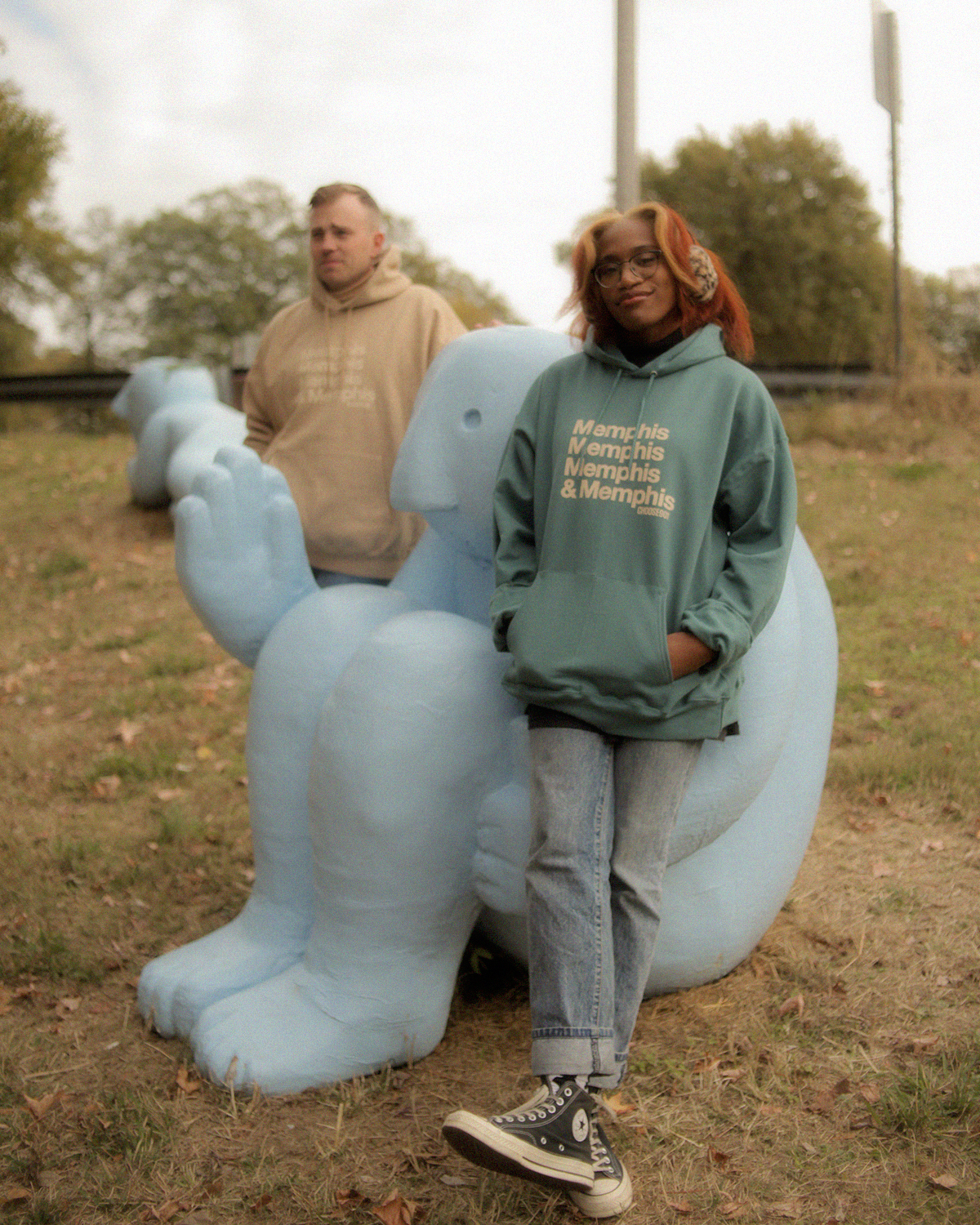 A man and woman standing next to a blue statue.