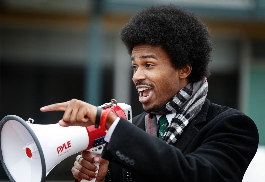 A man with an afro spreads good news and yells into a megaphone in Memphis.