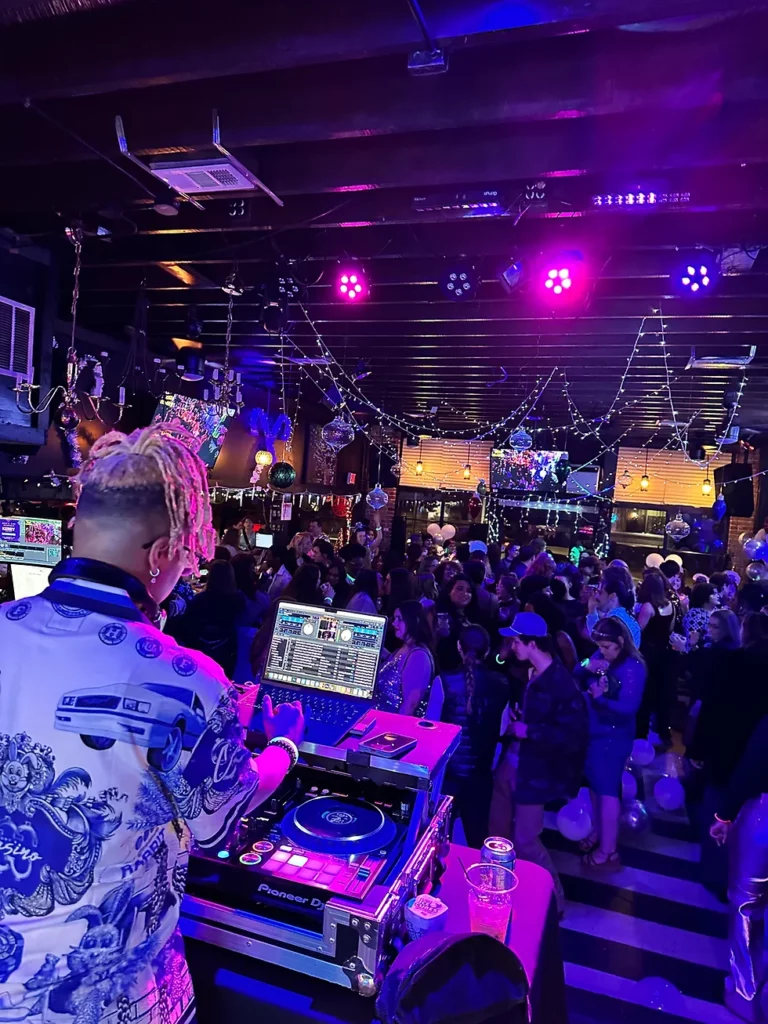 A DJ at a bar in Memphis, creating hot spots of energy with a crowd of people.
