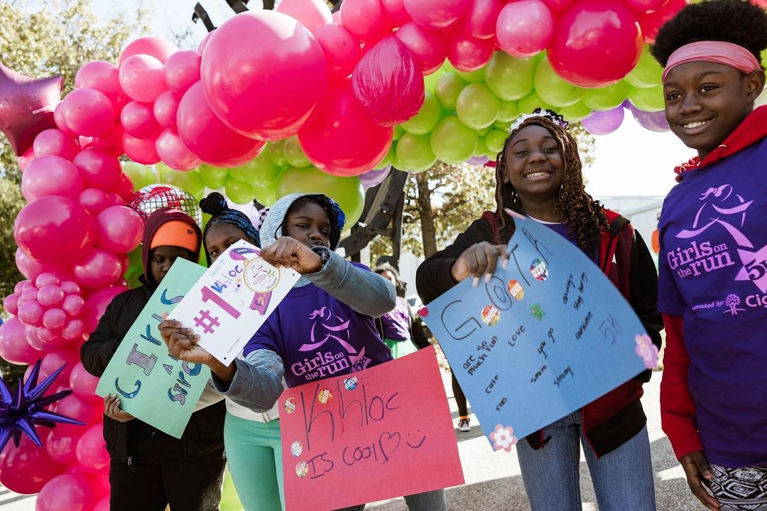 A group of girls holding balloons and signs to serve Memphis this month.