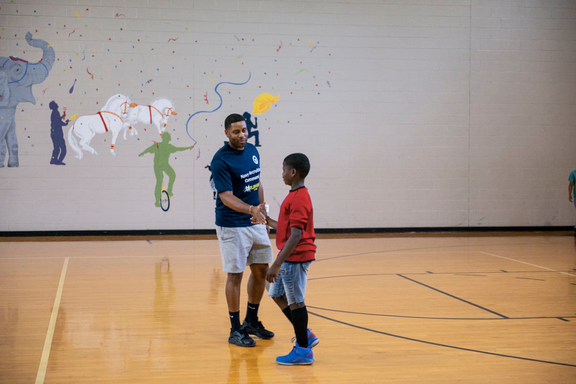 A mentor is talking to a young boy in a gym in Memphis.