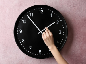 A woman's hand is touching a clock in a learning environment.
