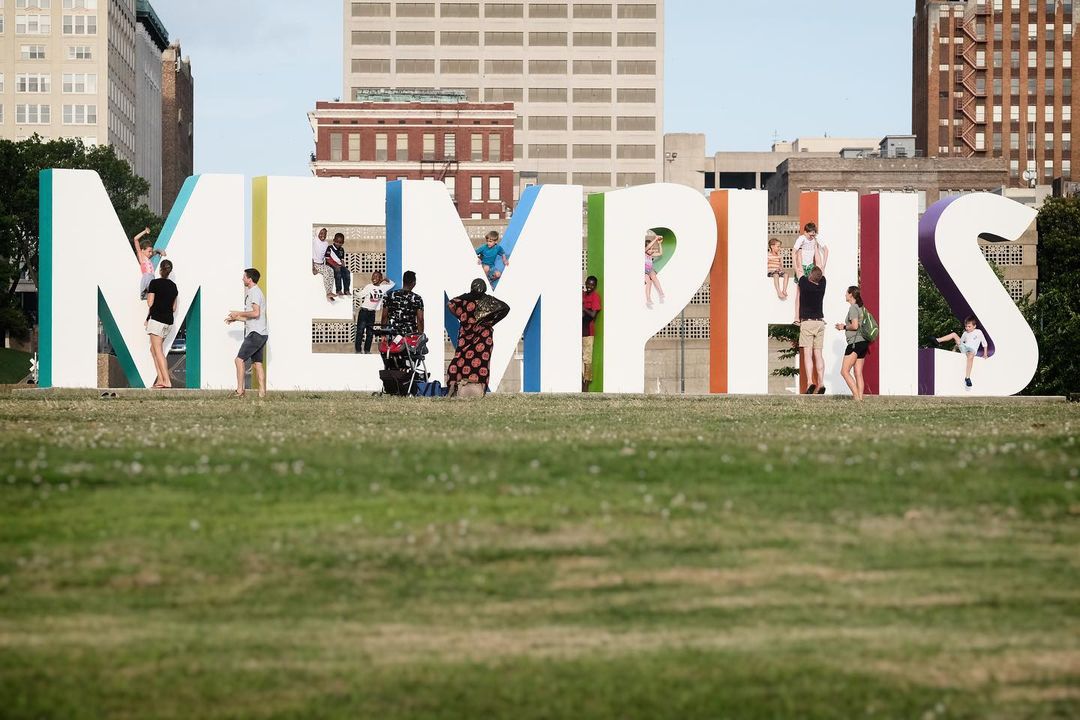 A group of people standing in front of a colorful memphis sign supporting 4 Local Nonprofits.