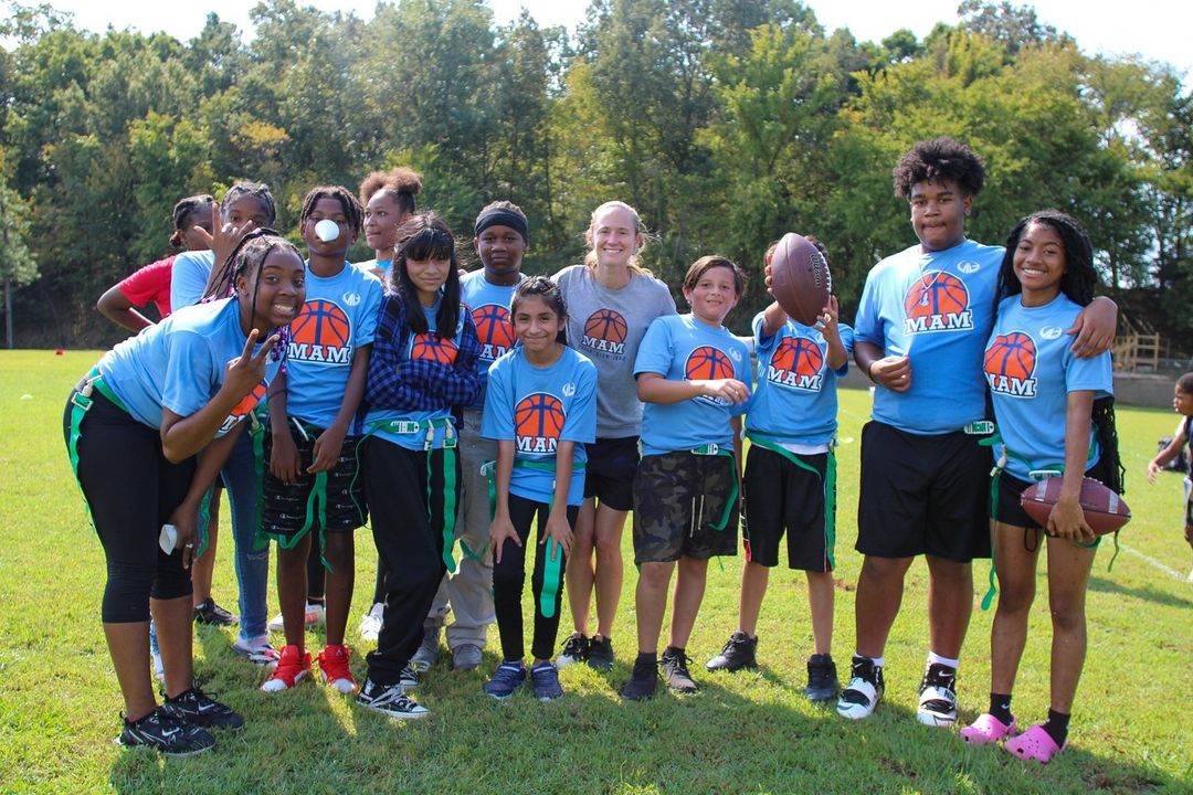 A group of young people posing for a photo at the MAM Center field.