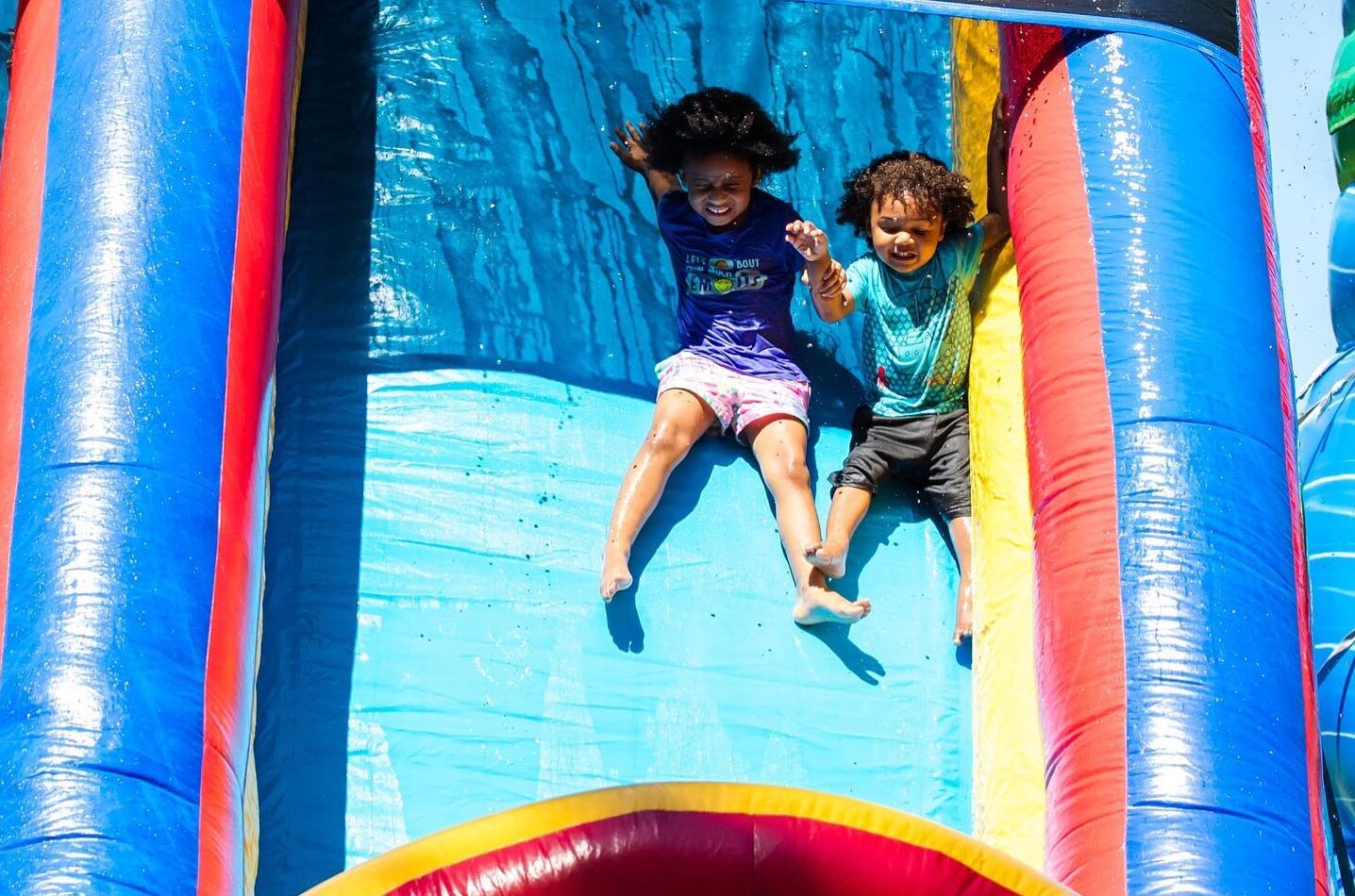 Two children enjoy a slide at a carnival.