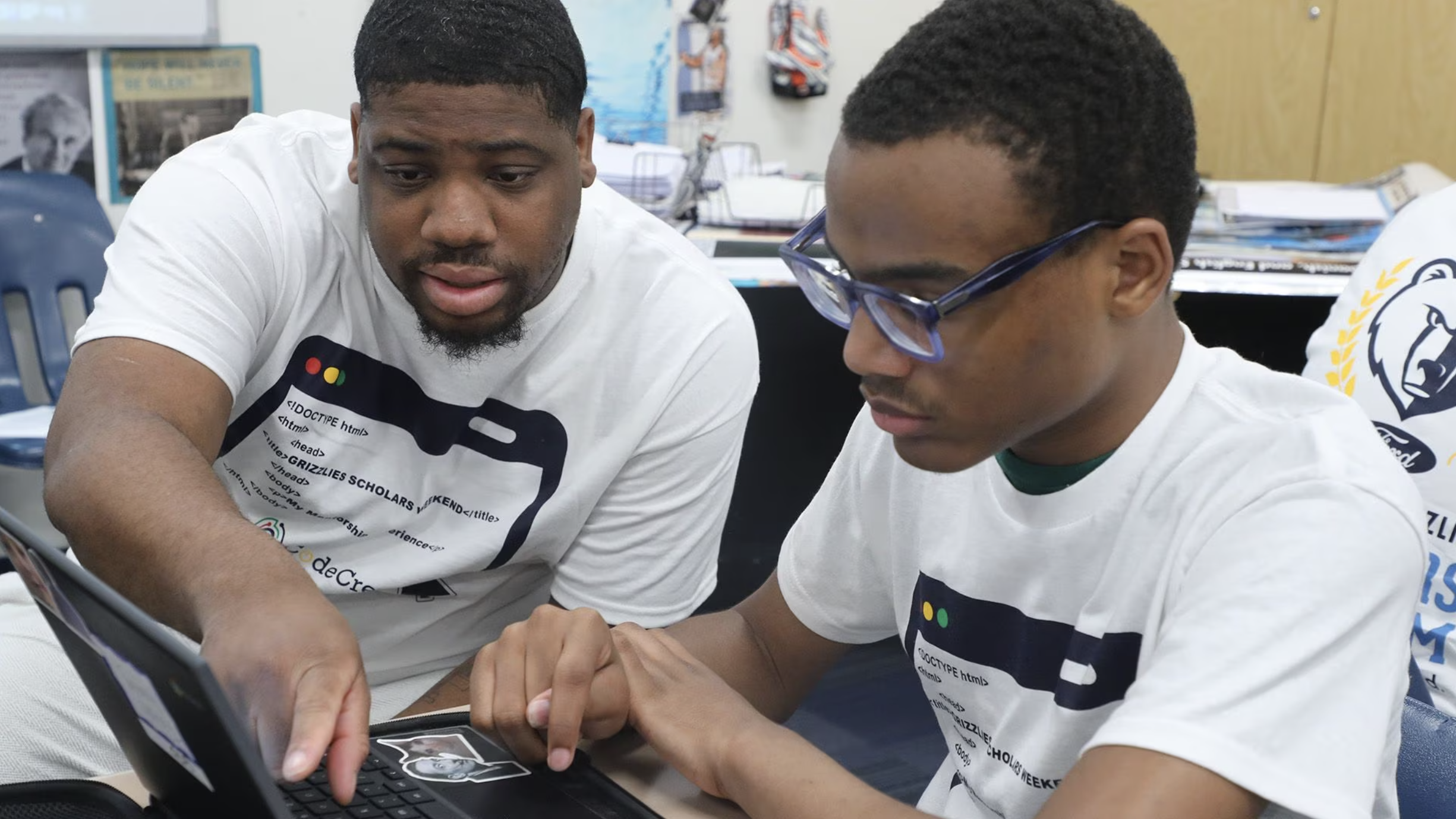 Two young men working on a laptop in a classroom, exploring summer service opportunities in Memphis.