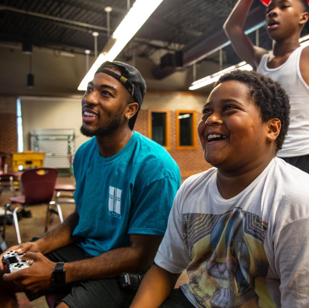 A group of boys engaged in a video game session in a classroom during summer.