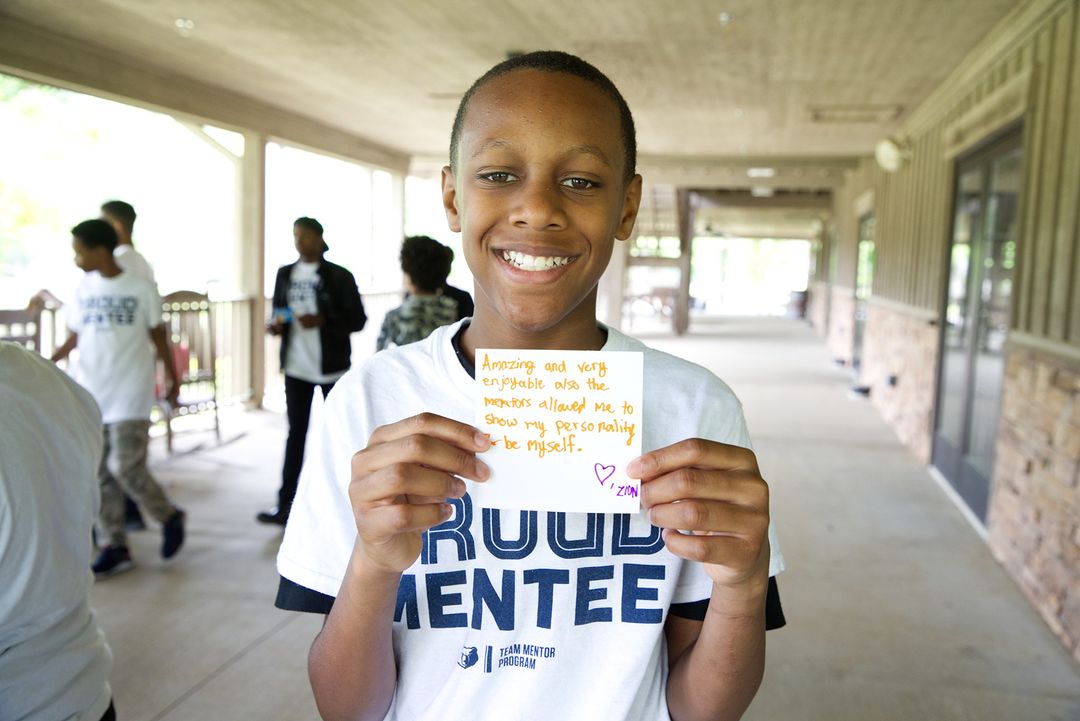 A young boy holding up a sign that says proud tenten during Summer Service Opportunities in Memphis.