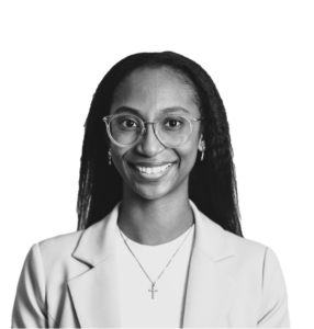 A black and white photo of a woman wearing glasses and a blazer, looking professional and poised.
