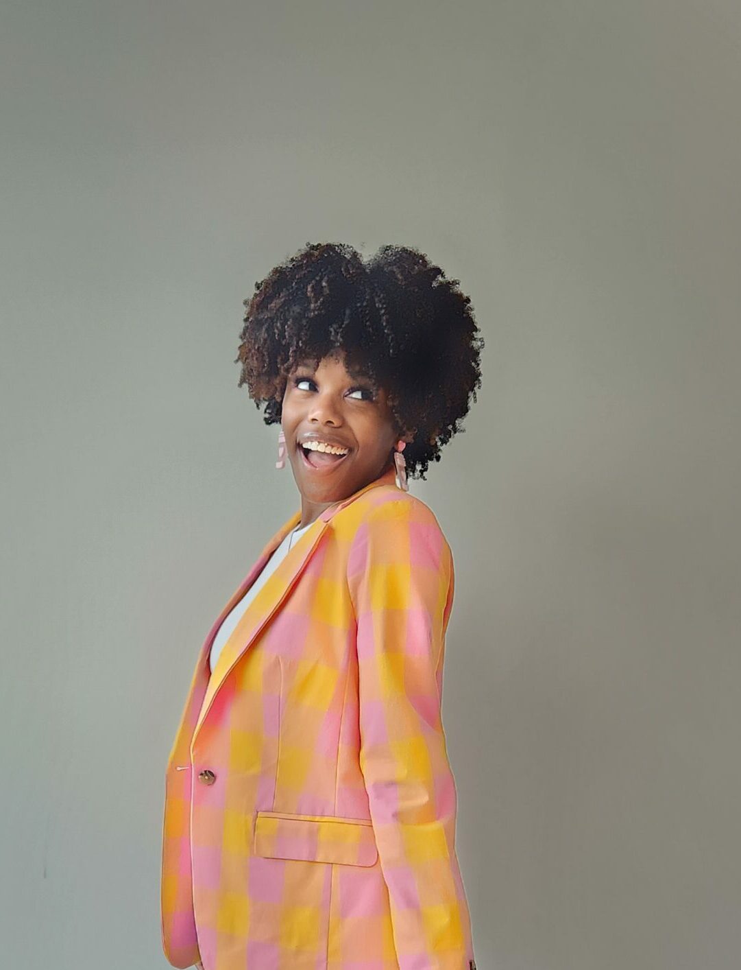 A woman in a pink and yellow blazer posing for a photo at NexGen.