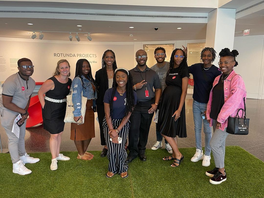 A group of people posing for a photo in an art gallery during Get to Know NexGen Darius Rosser event.