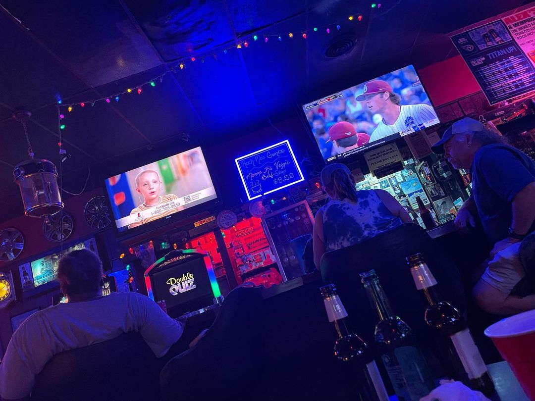 A Memphis Watch Party with a group of people sitting at a bar watching televisions.