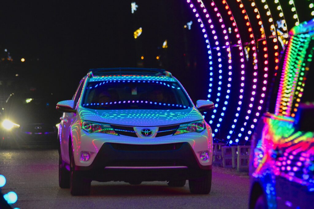 A Toyota RAV4 driving down a street adorned with colorful lights during Starry Nights Memphis.