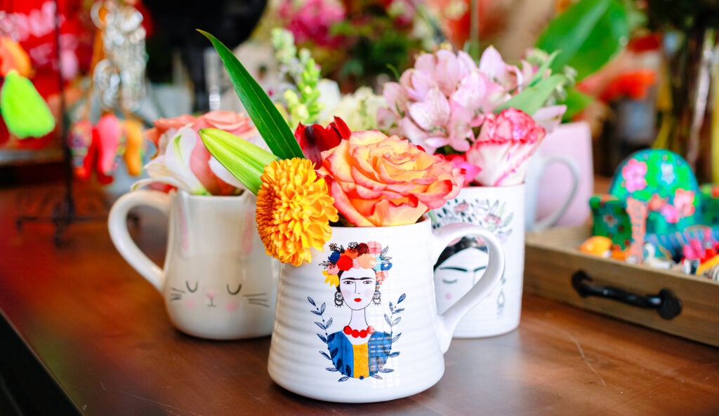 Three festive mugs adorned with flowers sit on a table, bringing the holiday season vibes.